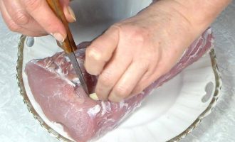 Чеснок разрезать и вставить в мясо